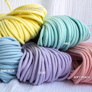 May include: A selection of colourful macrame cord in bundles. The colours include light yellow, mint, baby blue, lilac, and soft peach. Text labels read "LIGHT YELLOW", "MINT", "BABY BLUE", "LILAC", and "SOFT PEACH".