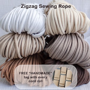 May include: A collection of zigzag sewing rope in various neutral colors, including white, beige, tan, and brown. The image includes text that reads "Zigzag Sewing Rope" and "FREE 'HANDMADE' tag with every cord roll."