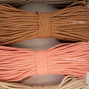 May include: Close-up of four bundles of cotton rope in various colours. The colours include latte, caramel, soft peach, and natural. Each bundle is tightly wound and labelled with its respective colour name.