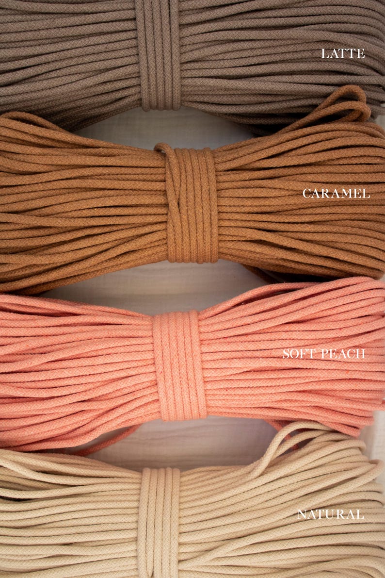 May include: Close-up of four bundles of cotton rope in various colours. The colours include latte, caramel, soft peach, and natural. Each bundle is tightly wound and labelled with its respective colour name.