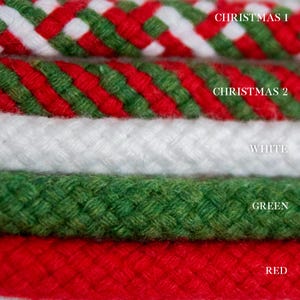 May include: Close-up of six braided ropes in various colours. The top two ropes are Christmas-themed, with red, green, and white patterns. The other ropes are white, green, and red. Text labels identify each colour.