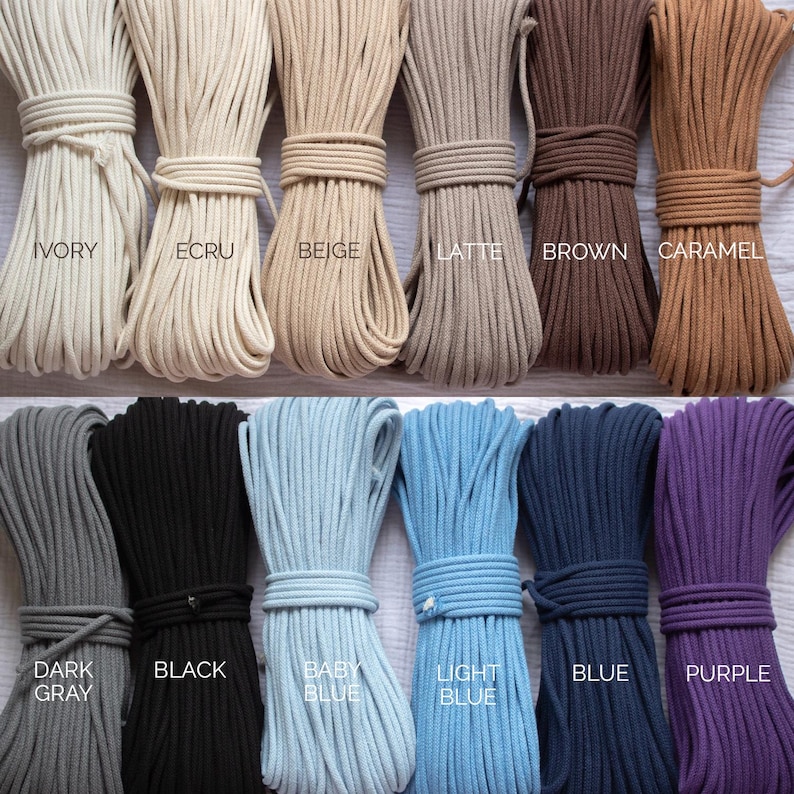 May include: A range of macrame cords in colours such as ivory, ecru, beige, latte, brown, caramel, dark grey, black, baby blue, light blue, blue, and purple. Each bundle is neatly tied.