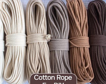 May include: Several bundles of cotton rope in shades of cream, beige, grey, and brown. Each bundle is neatly bound with matching rope. The image features the text "Cotton Rope For DIY".