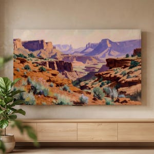 Op de afbeelding: Een rechthoekige wandkunstprint met een woestijncanyonlandschap met gelaagde oranje rotsformaties, dieppaarse schaduwen en schaarse groene woestijnvegetatie onder een bleke lucht, gemonteerd op een muur boven een lichthouten mediaconsole.
