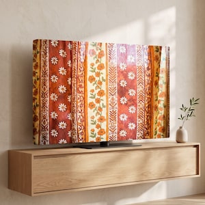 May include: A television screen displaying a vibrant, vertical-striped pattern featuring alternating bands of deep rust-orange with white daisy motifs and cream-coloured sections adorned with delicate orange floral vines and geometric chevron borders.