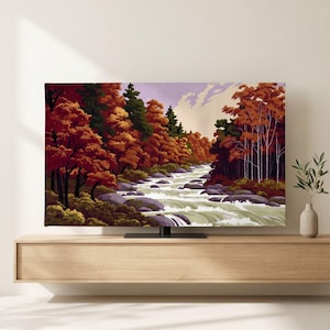 Könnte beinhalten: Ein Flachbildfernseher, der ein Landschaftsgemälde eines reißenden Flusses zeigt, der durch einen Wald mit herbstlich gefärbten Bäumen in Orange-, Rot- und Grüntönen fließt, vor einem hellvioletten und cremefarbenen Himmel mit Felsen.