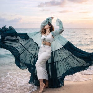 May include: A white two-piece set consisting of a sleeveless crop top and a high-waisted midi skirt, paired with a long, sheer, tiered duster robe that transitions from light teal at the shoulders to a deep forest green at the hem.