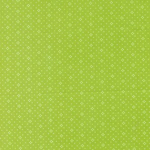 May include: Close-up of a lime green fabric with a repeating pattern of small white floral-like shapes. The fabric has a textured appearance, with a subtle grid-like weave visible throughout the material. The overall design is simple and clean.