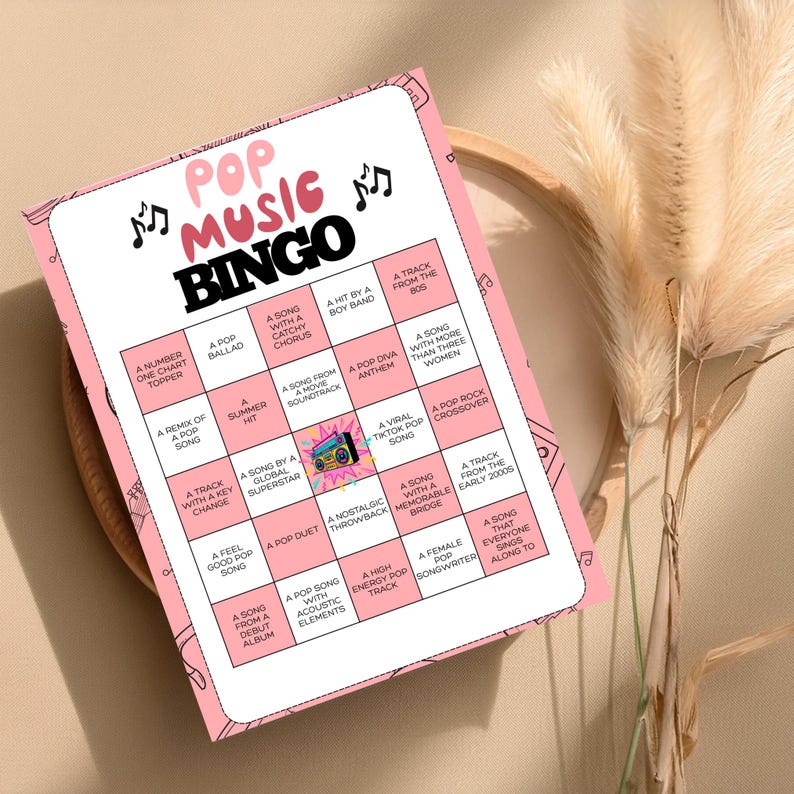 May include: A pink Pop Music Bingo game card with black text and musical note graphics. The card features various bingo squares with phrases like "A Pop Diva Anthem" and "A Song From a Debut Album."