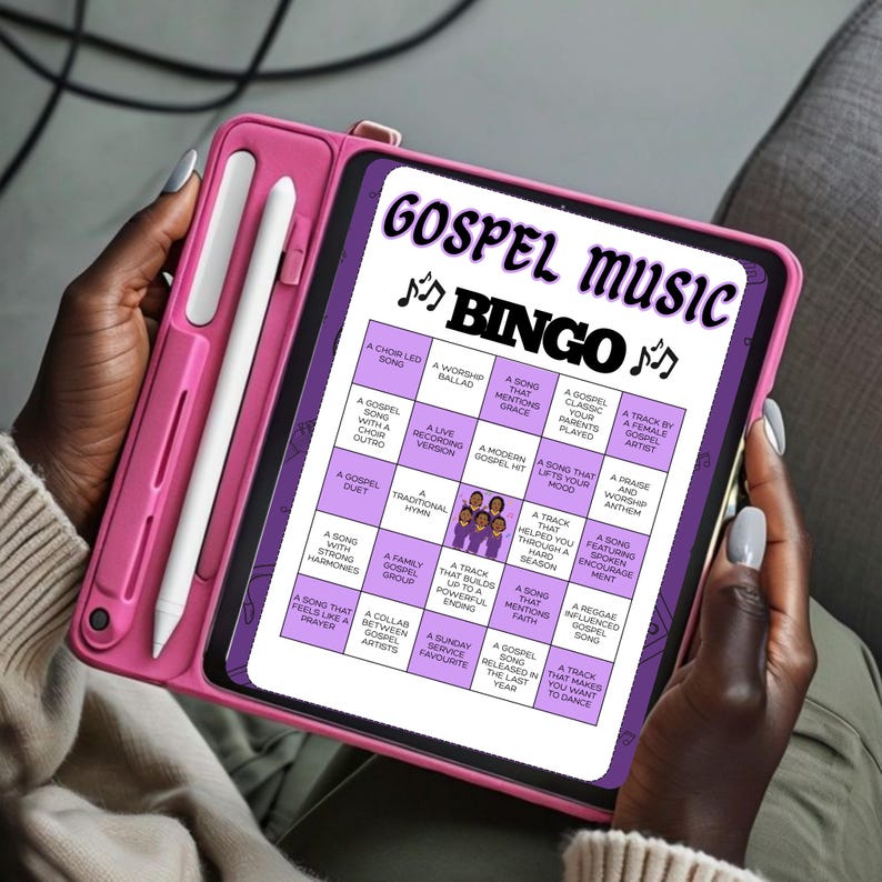 May include: A pink tablet case holding a tablet with a Gospel Music Bingo game displayed on the screen. The game board features various gospel music-related phrases. A white stylus is attached to the case.