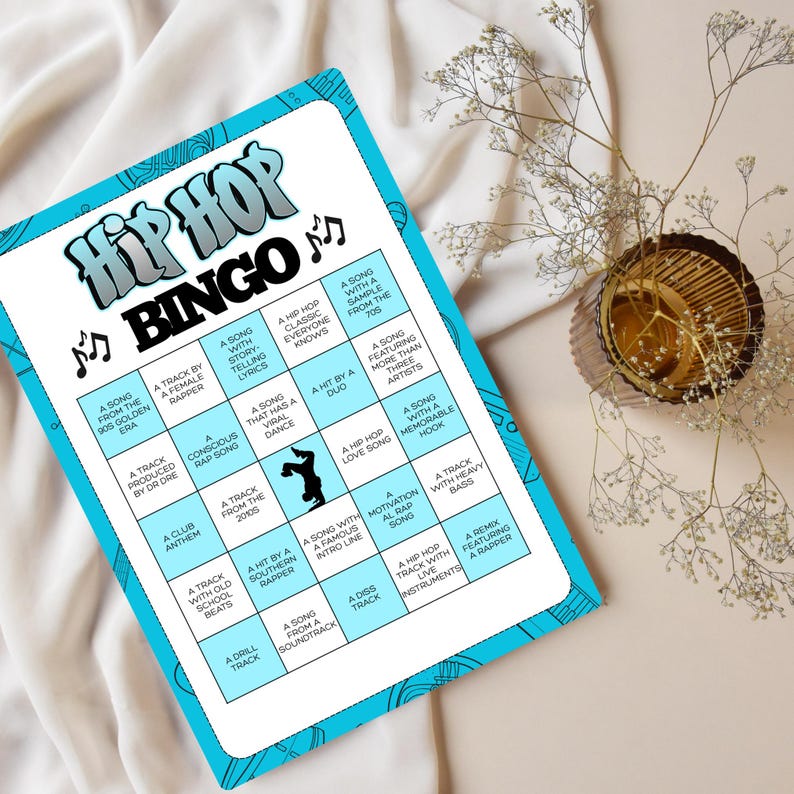 Op de afbeelding: Een Hip Hop Bingo-spelkaart met een blauwe rand en een witte binnenkant. De kaart bevat de woorden "Hip Hop Bingo" in een gestileerd lettertype bovenaan. De kaart is gevuld met verschillende hiphop-gerelateerde zinnen.