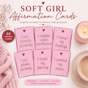 May include: Pink affirmation cards with phrases like "I am whole already" and "I radiate quiet confidence." The cards are labeled "SOFT GIRL Affirmation Cards" and are 3x4 inches and 4x6 inches. A lit candle and a cup of coffee are in the background.