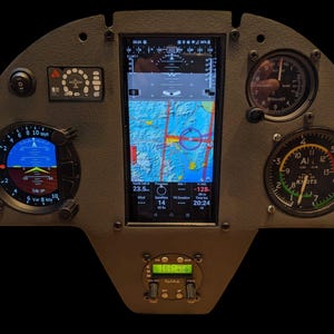 May include: A grey instrument panel featuring various gauges and a central screen showing flight data. The panel includes a digital display, altimeter, airspeed indicator, and other aviation instruments. The screen displays a map and flight information.