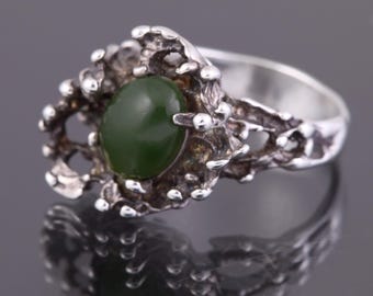 May include: A silver ring with a green stone set in a textured, organic design.