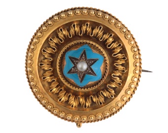 May include: A gold brooch with a blue enamel star and a pearl in the center. The star is surrounded by a gold border and a ring of gold leaves. The brooch is set in a gold frame with a beaded edge.