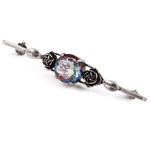 May include: Silver brooch with a large iridescent gemstone surrounded by three black rose accents.