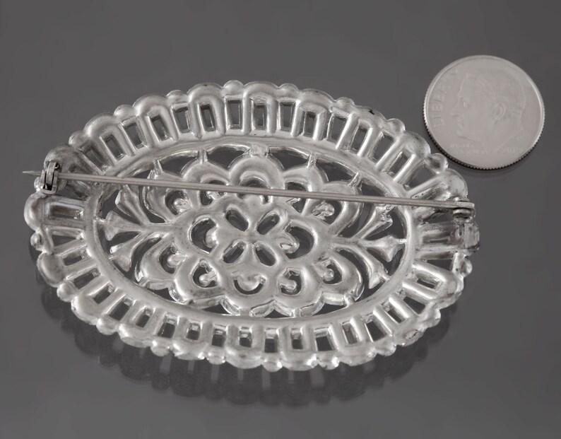 K&ouml;nnte beinhalten: Silberne Filigranbrosche mit floralem Design. Die Brosche hat eine Nadel und einen Verschluss auf der R&uuml;ckseite.