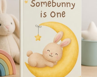 May include: A hardcover book with a cream-colored cover featuring the brown text Somebunny is One. The illustration shows a light brown bunny sleeping on a yellow crescent moon with a small hanging yellow star and several small stars.