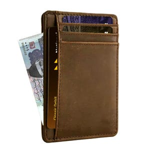 May include: A brown leather cardholder wallet with multiple card slots. A bill is partially visible, along with a "Classic Debit" card. The wallet is designed to hold cards and cash, and is made of a textured leather material.