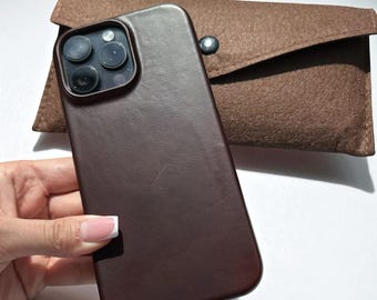 Op de afbeelding: Een donkerbruine leren telefoonhoes en een bijpassend bruin vilten etui. De telefoonhoes heeft een gladde textuur en een cameramodule met drie lenzen. Het etui heeft een klepsluiting met een zilveren drukknop.