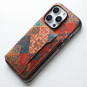 Puede incluir: Una funda de teléfono con un diseño estampado colorido. La funda presenta un accesorio de billetera con cierre de solapa. El patrón incluye formas geométricas rojas, azules, verdes y naranjas. La funda del teléfono es negra.