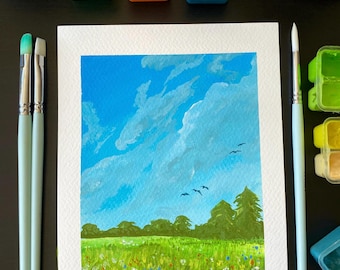 May include: A landscape painting of a blue sky with fluffy white clouds, green fields, and trees. Paintbrushes and paint containers with green, orange, and blue paint surround the artwork. The painting depicts a sunny day.