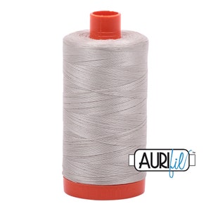 May include: A spool of silver gray thread with an orange plastic bobbin and the Aurifil logo on the side.