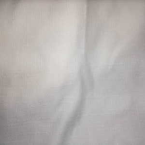 Könnte beinhalten: Weißer Stoff mit einer dezenten gewebten Textur. Der Stoff hat eine glatte, leicht zerknitterte Oberfläche.