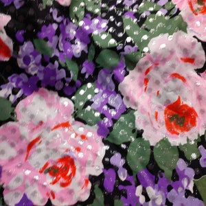 Könnte beinhalten: Ein schwarzer Stoff mit einem floralen Muster mit rosa, roten, violetten und grünen Blumen. Der Stoff hat eine silberne Glitzerauflage.