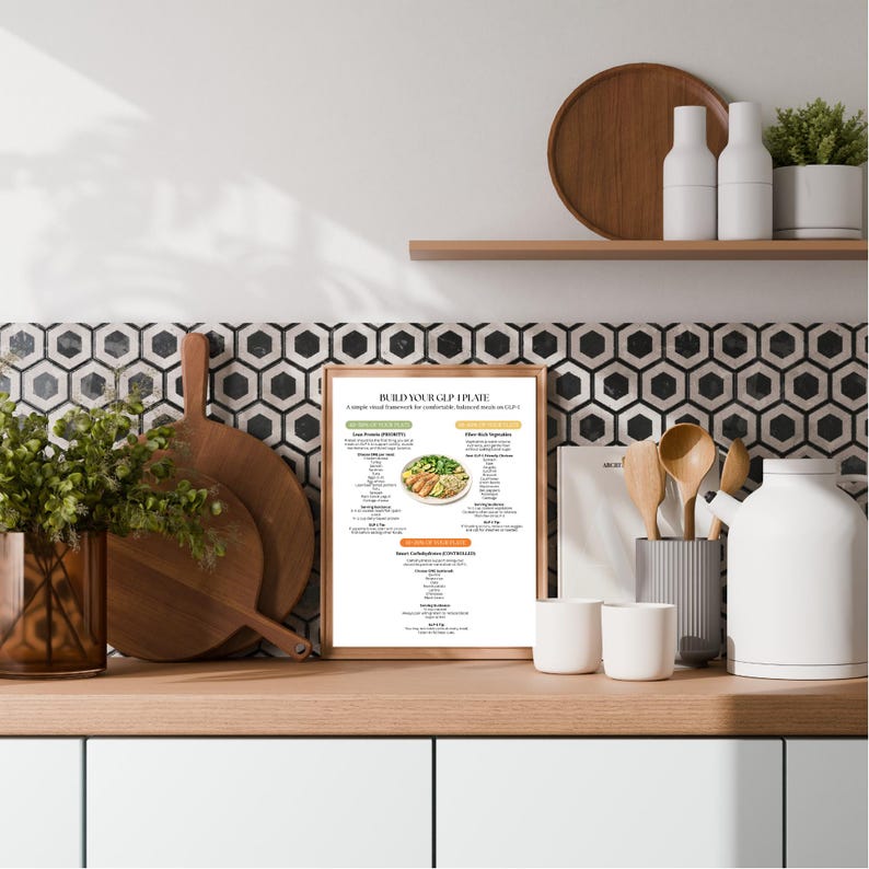 Puede incluir: Una impresi&oacute;n enmarcada titulada "BUILD YOUR CUP I PLATE" con un marco visual simple para una comida equilibrada. La imagen muestra una encimera de cocina con tablas de cortar de madera, utensilios y objetos decorativos. El fondo presenta un azulejo con estampado en blanco y negro.