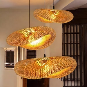 May include: Three woven bamboo pendant lights hanging from the ceiling. The lights are shaped like an oval with a twist in the middle. The lights are made of natural materials and have a rustic look.