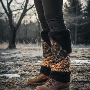 Puede incluir: Una persona con leggings negros y botas de cuero marrón con estampado de leopardo decorativo y puños de piel sintética negra. Las botas tienen cordones marrones y son adecuadas para actividades al aire libre.
