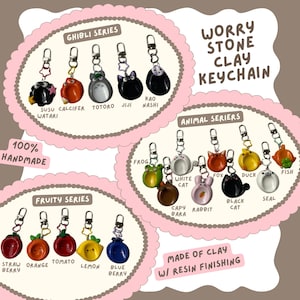 May include: Handmade clay keychains in various series: Ghibli, Animal, and Fruity. The Ghibli series features characters like Totoro and Jiji. The Animal series includes a frog, cat, and fox. The Fruity series showcases strawberry, orange, and blueberry designs. The keychains are made of clay with resin finishing.