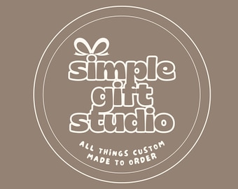May include: A circular logo with the text "simple gift studio" in white, with a bow graphic above the word "simple". The text "ALL THINGS CUSTOM MADE TO ORDER" is below the studio name, all on a brown background.