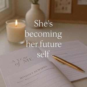 K&ouml;nnte beinhalten: Eine brennende Kerze in einem Glas, eine wei&szlig;e Vase mit Blumen und ein offenes Notizbuch mit einem goldenen Stift. Das Notizbuch tr&auml;gt den Text "A Year of Me" und "Mindset Rewires". Das Bild enth&auml;lt auch den Text "She's becoming her future self".