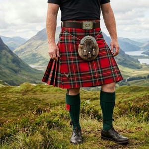 Puede incluir: Un kilt escocés tradicional con un patrón de cuadros rojos y verdes. Se lleva con un cinturón de cuero marrón, un sporran, calcetines verdes y zapatos negros. El fondo muestra un paisaje montañoso.