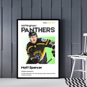 May include: A framed poster featuring a hockey player in a black and gold jersey with the text "PANTHERS." The player is wearing a helmet and holding a hockey stick. The poster includes the player's name, "Matt Spencer," and a description of his role.
