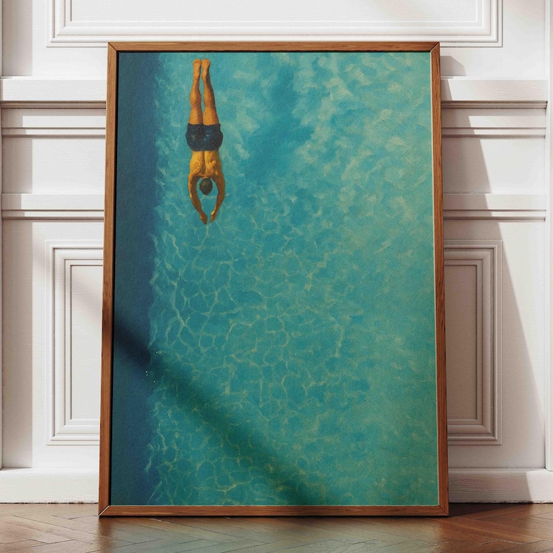 May include: A framed art print depicts a person diving headfirst into a turquoise pool. The diver, wearing dark blue swim trunks, is positioned upside down. The artwork has a vintage, textured appearance, with a wooden frame.