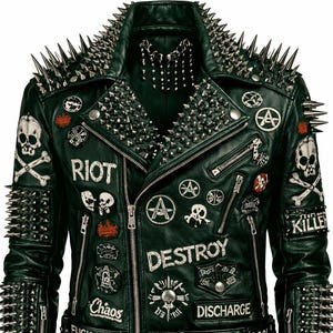 Könnte beinhalten: Dunkelgrüne Lederjacke mit silbernen Stacheln an Schultern, Kragen und Ärmeln. Die Jacke hat Aufnäher mit Texten und Symbolen, darunter Totenköpfe, Anarchiesymbole und die Worte "RIOT" und "DESTROY".