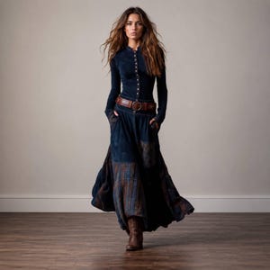 May include: A long-sleeved dark blue button-down top paired with a matching floor-length skirt featuring a plaid pattern at the hem. The outfit includes a wide brown leather belt with a circular buckle and brown lace-up boots.