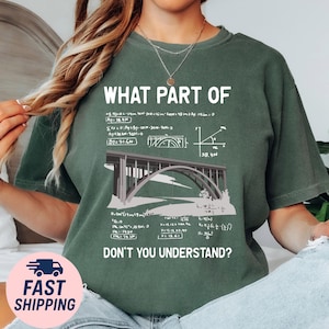 May include: Green t-shirt featuring the text "WHAT PART OF DON'T YOU UNDERSTAND?" and a bridge illustration with mathematical elements. The design includes equations and diagrams. The shirt has a relaxed fit.