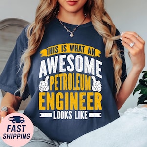 May include: Navy blue t-shirt with the text "THIS IS WHAT AN AWESOME PETROLEUM ENGINEER LOOKS LIKE" in white and yellow. The shirt features a thumbs-up graphic on each side of the text.