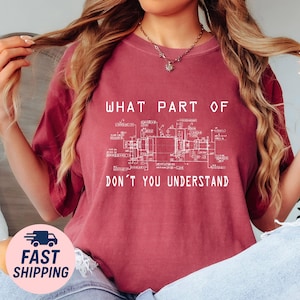 May include: Burgundy-colored t-shirt with the text "WHAT PART OF DON'T YOU UNDERSTAND" above a white blueprint design. The shirt is a casual style, suitable for everyday wear.