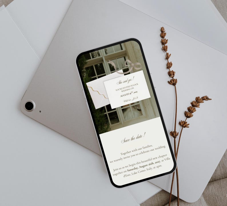 May include: A smartphone displaying a digital wedding invitation with the text She said yes! You're invited to our wedding on August 26th, 2027, and Save the date! Together with our families, we warmly invite you to celebrate our wedding.