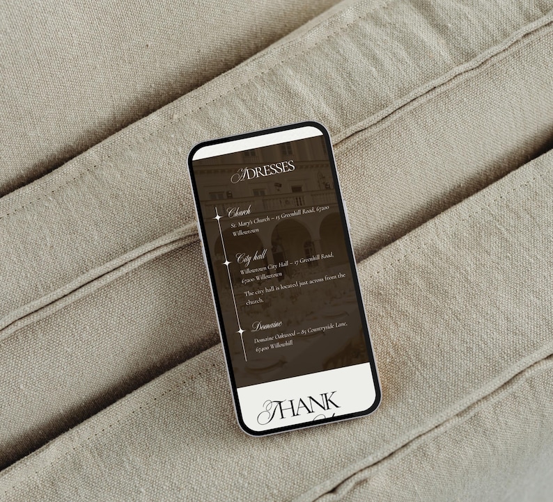 May include: A smartphone displays a list of addresses for dresses, including a church, city hall, and a domaine. The screen has a dark background with white text and a decorative font. The phone is on a beige fabric surface.