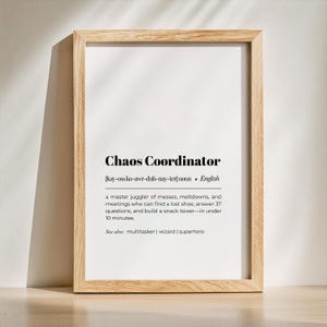Può includere: Stampa incorniciata con le parole "Chaos Coordinator" in grassetto nero. La definizione descrive un maestro giocoliere di disastri. La cornice è in legno chiaro e lo sfondo è bianco.