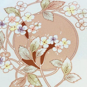 K&ouml;nnte beinhalten: Blumenmuster mit einem pfirsichfarbenen Kreis in der Mitte, umgeben von wei&szlig;en Bl&uuml;ten mit gelben, rosa und violetten Zentren. Das Design umfasst gr&uuml;ne und hellbraune Bl&auml;tter und Stiele, alles vor einem wei&szlig;en Hintergrund.