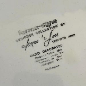 K&ouml;nnte beinhalten: Nahaufnahme eines wei&szlig;en Keramiktellers mit schwarzem Text. Der Text lautet "forma-stone DESIGNER COLLECTION of fermer '2' Love TERESITA". Zus&auml;tzlicher Text weist darauf hin, dass der Teller handdekoriert, ofen- und mikrowellengeeignet und sp&uuml;lmaschinenfest ist.