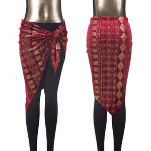 May include: A red and gold patterned wrap skirt with a knotted tie, paired with black leggings. The skirt features a geometric design and drapes over the leggings. The second view shows the skirt from the back.