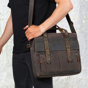 May include: A brown leather messenger bag with a shoulder strap and a top handle. The bag features two front pockets with zips and two buckle straps. The bag is made of a durable material and is designed for carrying items.